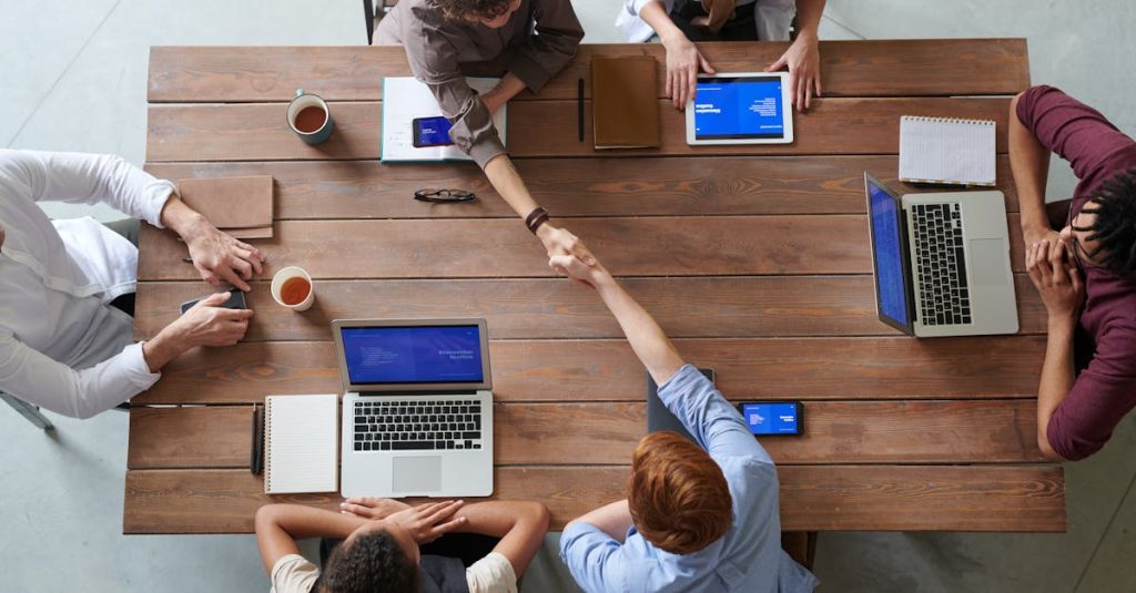 Overhead view of colleagues in a work meeting using laptops and tablets, emphasizing teamwork and technology.